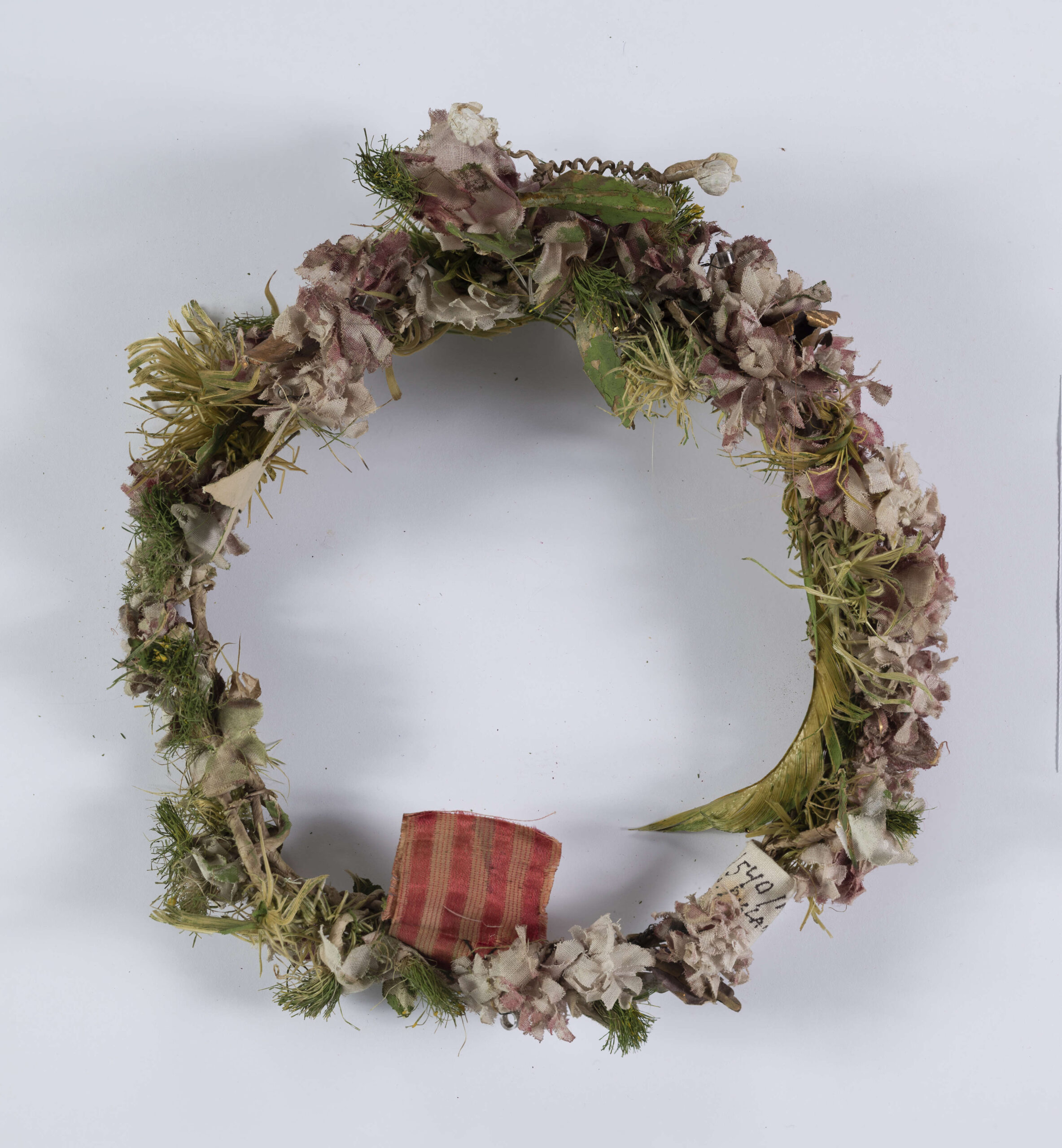 Ubiór głowy kobiecy w formie wianka wykonany z różnokolorowych kwiatów z płótna oraz zielonych listków. Całość umocowana na drucie.