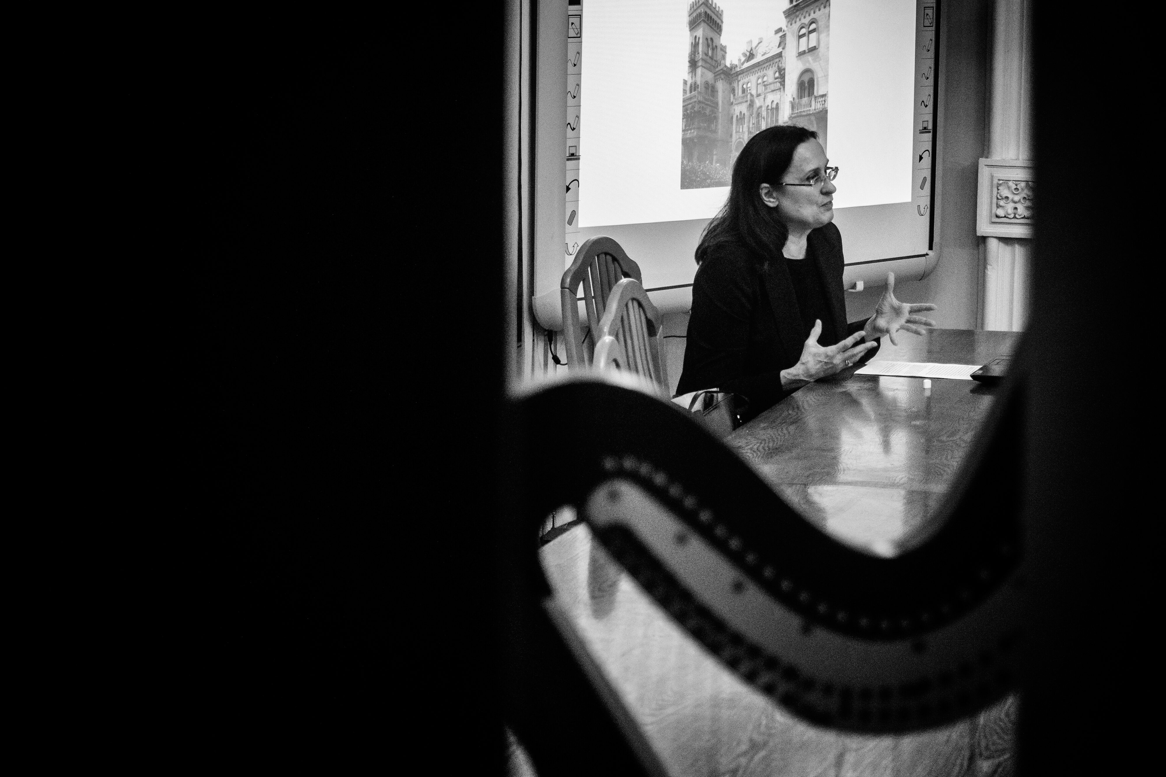 Czarno białe zdjęcie. W centrum dr Lidia Kwiatkowska-Frejlich siedząca przy stole,wygłaszająca wykład
