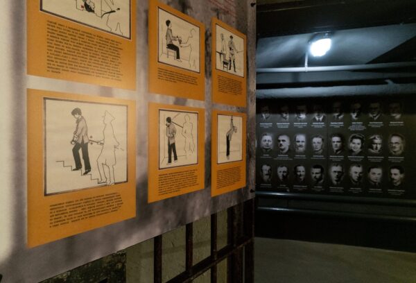 widok na plansze z lewej opisy z poglądowymi rysunkami zachowań niemców w stosunku do więźniów na przeciw plansza ze zdjęciami portretowymi więźnów
