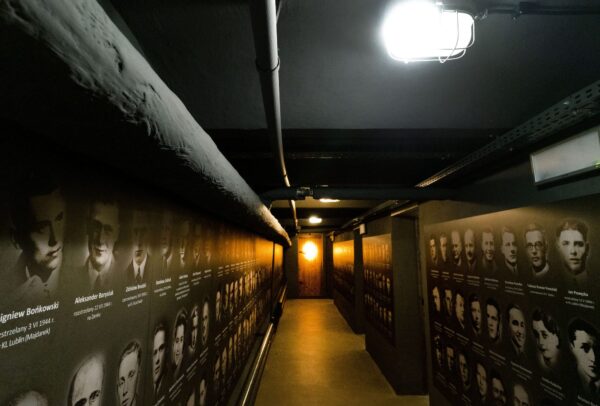 korytarz po bokach plansze z wizerunkami więźniów