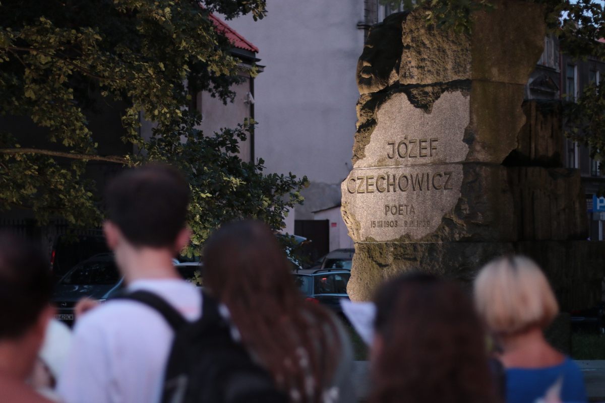 widok na pomnik j.czechowicza i stojące tyłem sylwetki ludzi