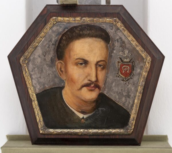 Portret przedstawiający wąsatego mężczyznę na posrebrzanym tle. Blisko jego twarzy namalowany herb Lubicz.