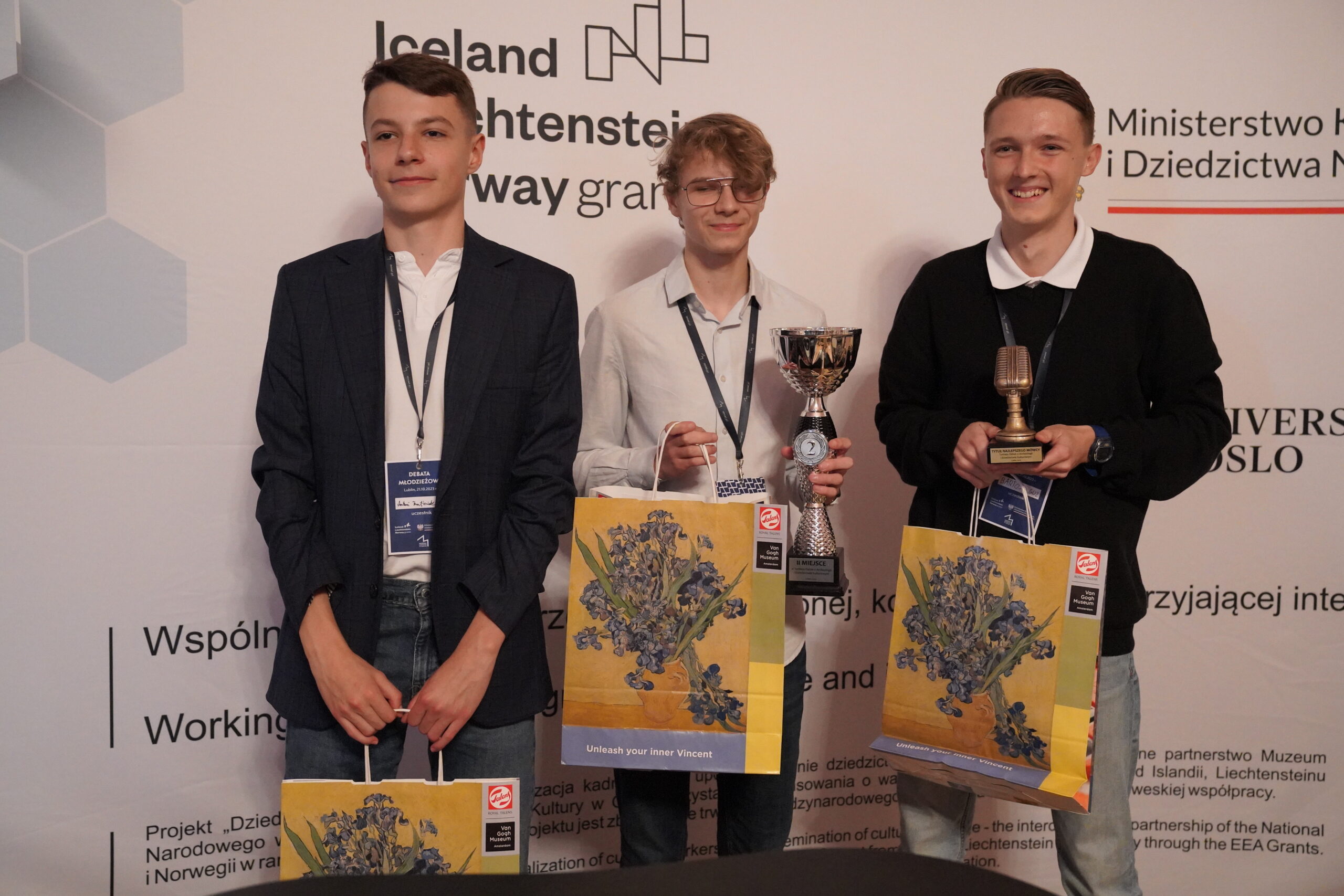 Zdjęcie zwycięskiej drużyny - trzech uśmiechniętych chłopaków trzymających w rękach nagrody